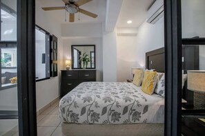 Ein Schlafzimmer mit Bett, Deckenventilator, Spiegel und Kommode.