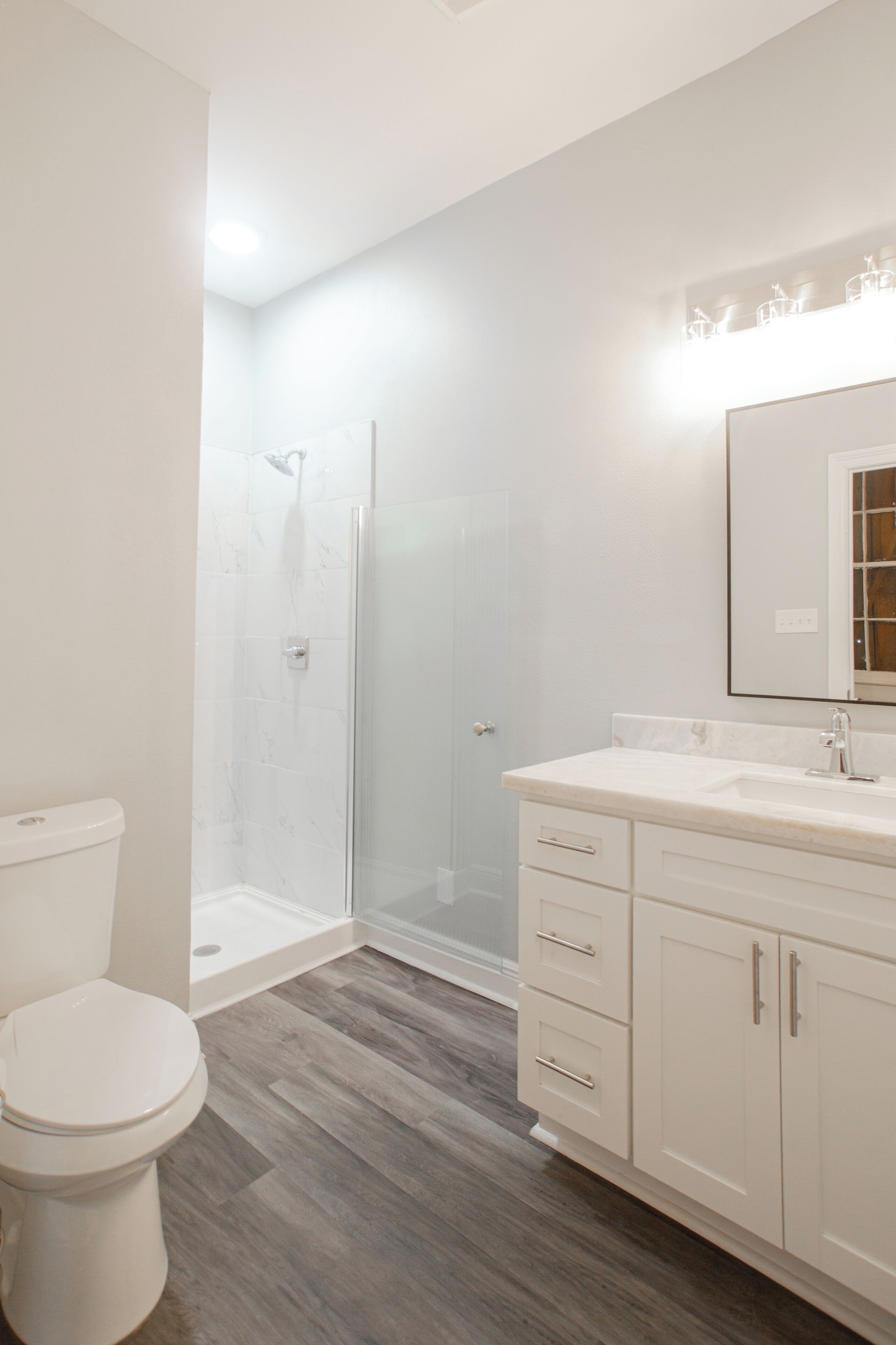 A modern bathroom with a shower, toilet, and vanity.