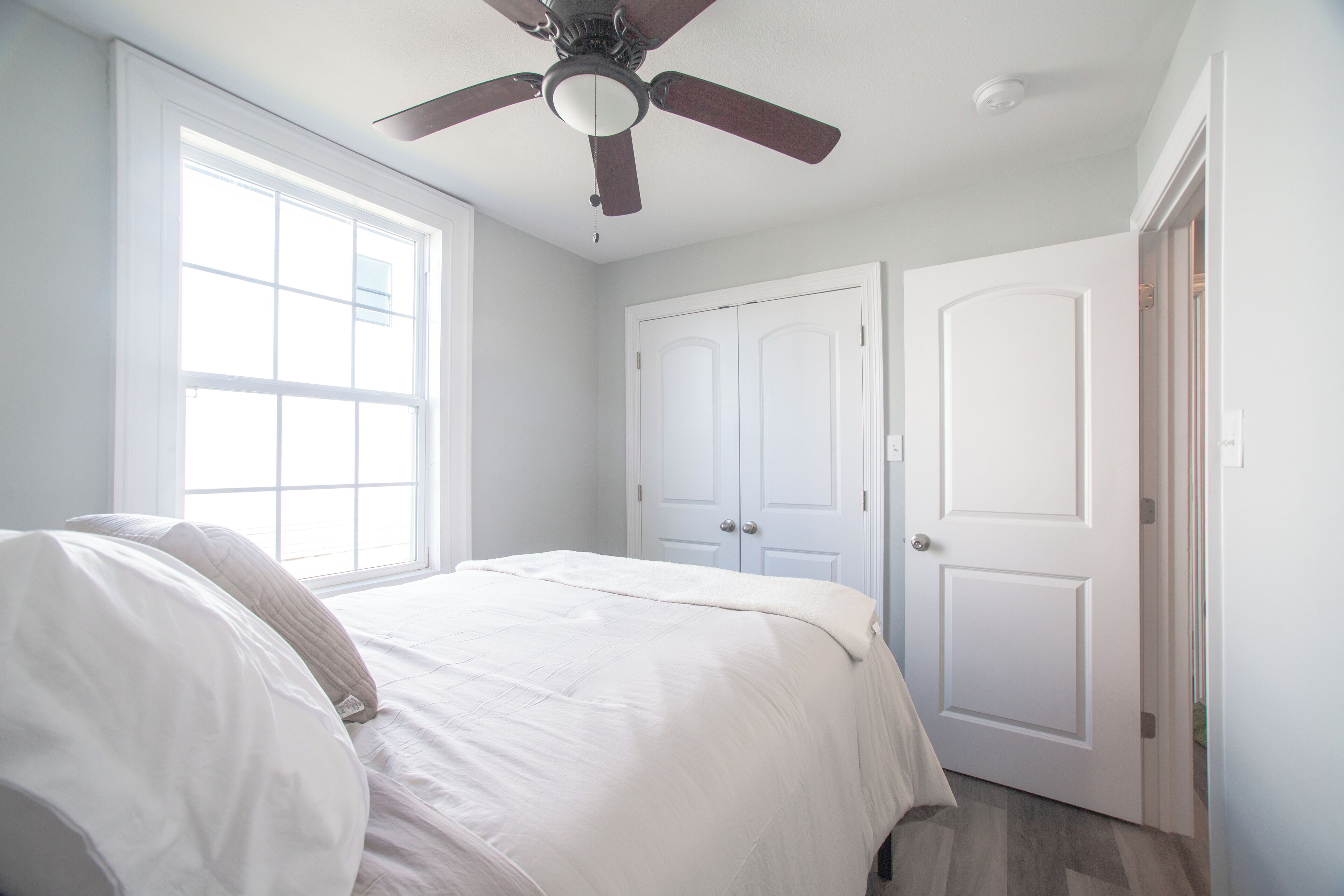 Un dormitorio con cama, ventilador de techo y dos puertas.