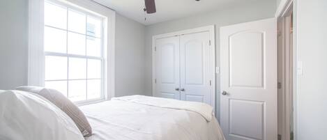 Un dormitorio con cama, ventilador de techo y dos puertas.