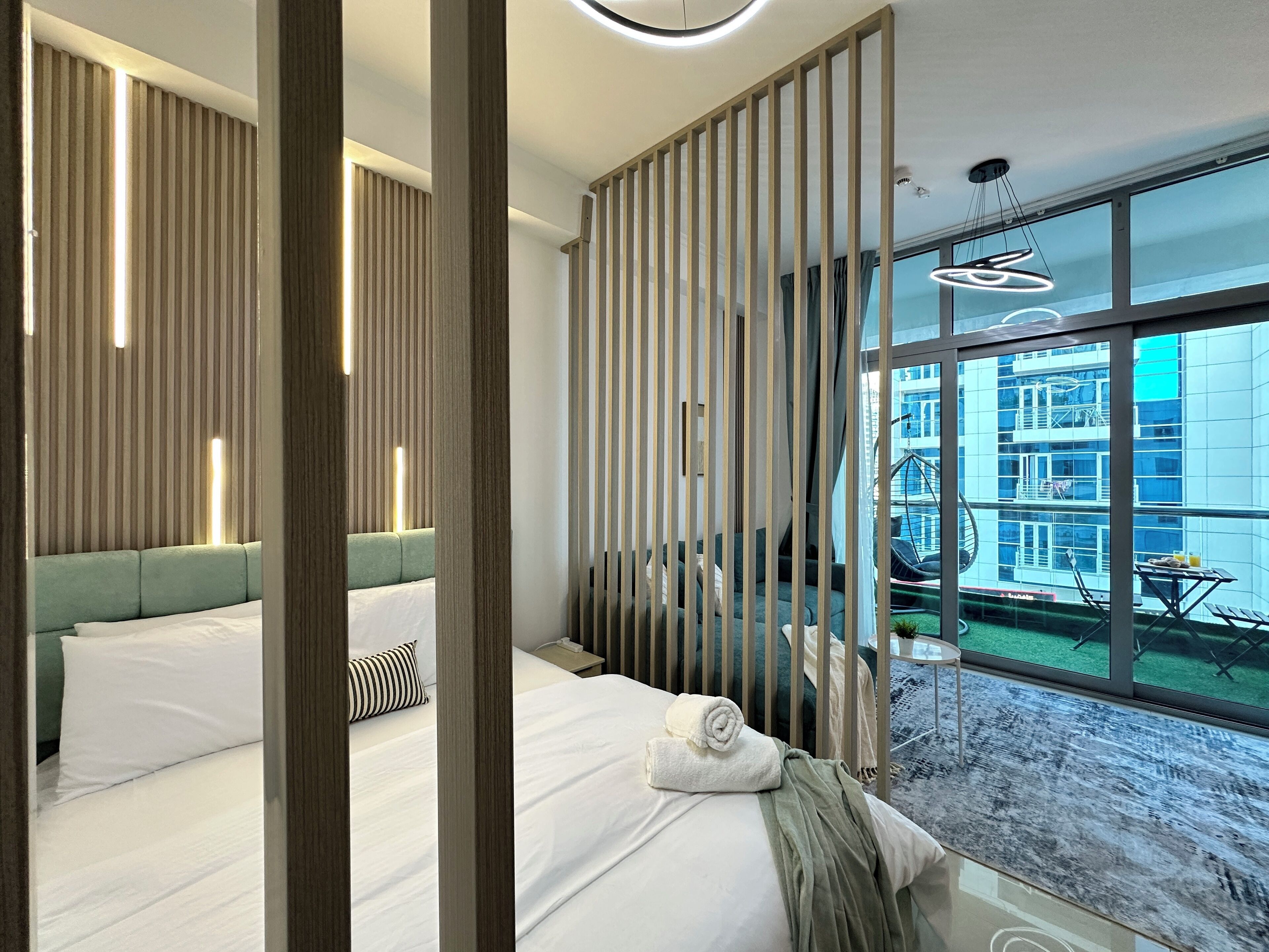 Een moderne hotelkamer met een groot bed, uitzicht op de stad en een balkon met tuinmeubilair.