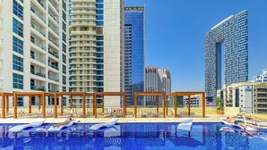 Una piscina sul tetto con lettini prendisole e un pergolato, circondata da grattacieli.