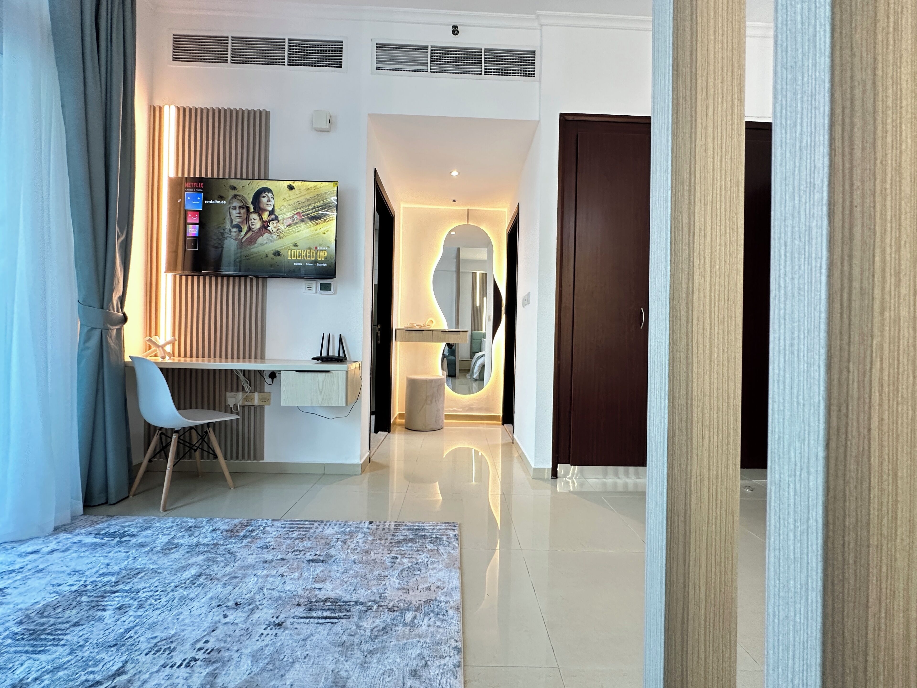 A modern living room with a flat-screen TV, a desk, and a comfortable seating area.