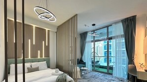 Camera moderna con un letto grande, una scrivania e vista sulla città attraverso ampie finestre.