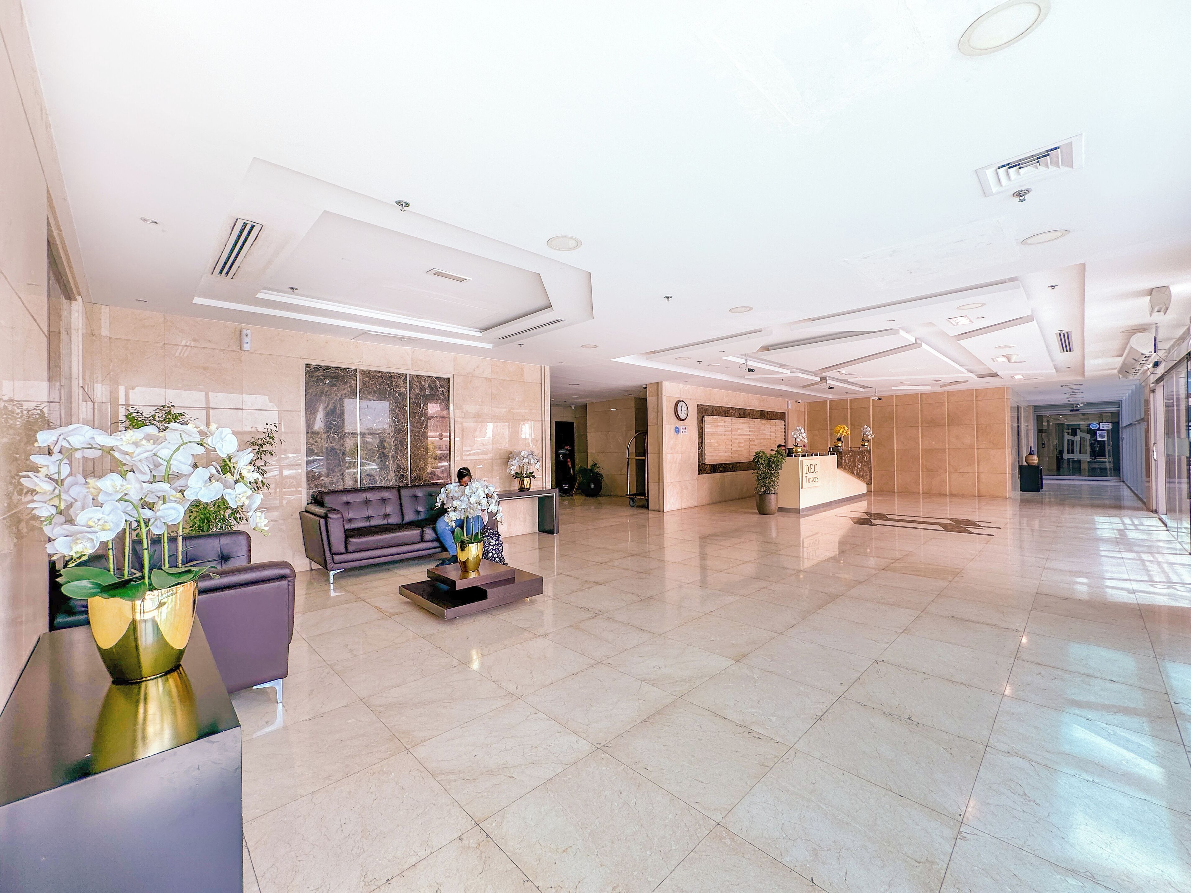 A spacious lobby with a reception desk, a sofa, and decorative plants.