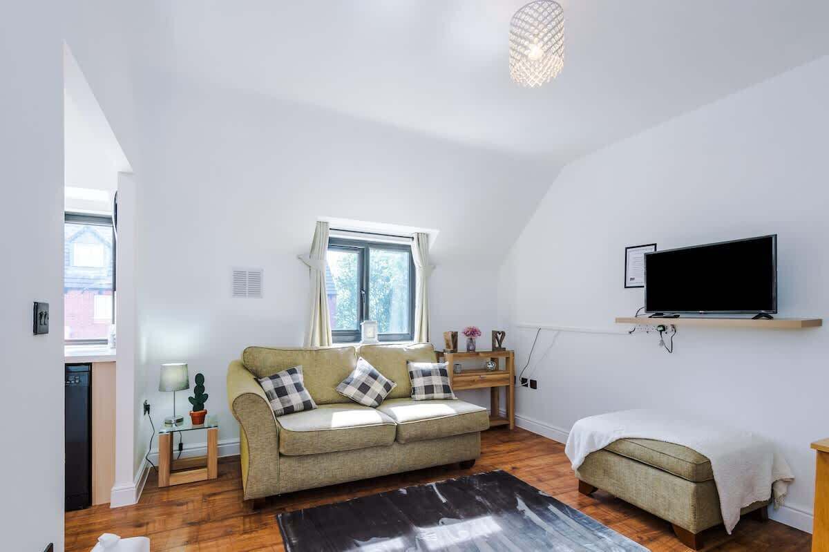A living room with a sofa, a TV, a window, and a small table.