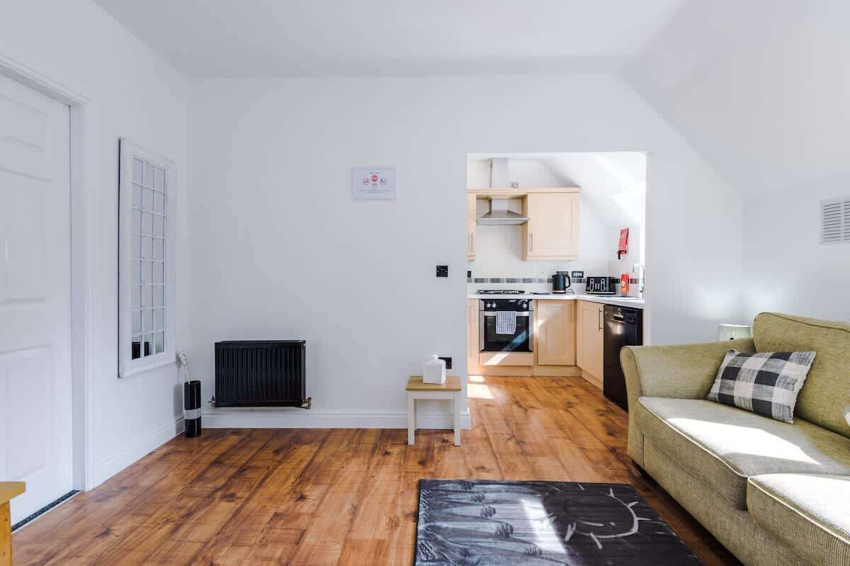 Un espace de vie compact comprenant un coin cuisine, un canapé, un radiateur et une petite table.