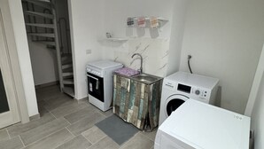 A compact laundry room with a washing machine, a dryer, and a small sink. - Holiday Properties nei Sassi Home (Matera)