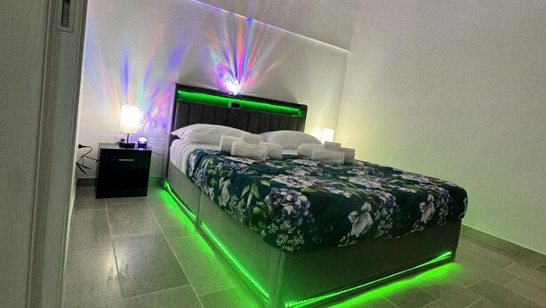 A modern bedroom with a bed, nightstands, and ambient lighting. - Holiday Properties nei Sassi Home (Matera)