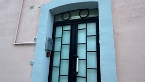 A building facade with a large, black-framed window and a white door. - Holiday Properties nei Sassi Home (Matera)