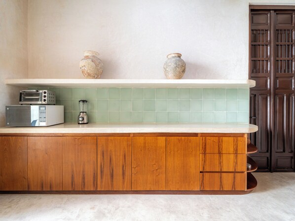 A kitchen with a wooden cabinet, a microwave, a blender, and two ceramic vases on a shelf. - Casa Bolero Santa Lucia, with Parking by Cercana (Mérida)