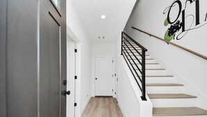 Eine moderne Treppe mit Holzbodenstufen und schwarzen Geländern, die zu einer weißen Tür oben führt.