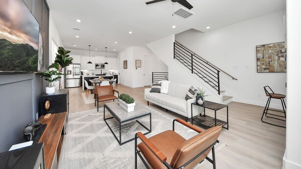 Ein modernes Wohnzimmer mit Sofa, Couchtisch und Sesseln. Eine Treppe führt zu einer weiteren Ebene.