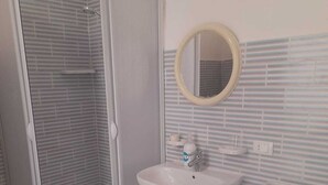 Ein Badezimmer mit Duschkabine, Waschbecken, Bidet und Spiegel.