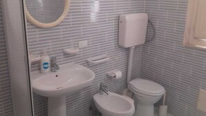 Ein Badezimmer mit Waschbecken, Bidet, Toilette und Spiegel.