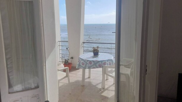 Ein Balkon mit Tisch und Stühlen mit Blick auf das Meer.