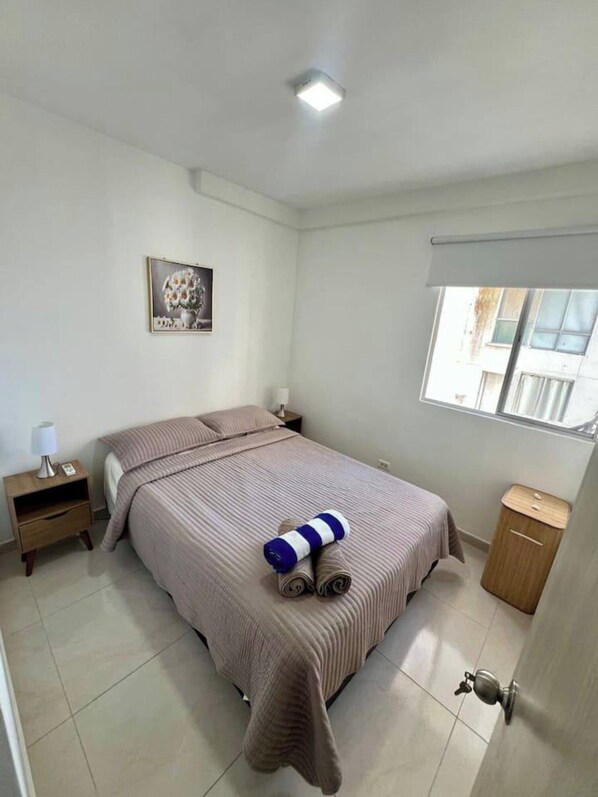 A bedroom with a bed, a nightstand, a lamp, a picture on the wall, a window, and a door. - Hermoso alojamiento centro (Cartagena)