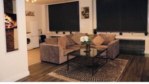 A living room with a sectional sofa, a coffee table, and a fireplace. - Cosy 3-Bedroom Family Apartment - Free Parking (Birmingham)