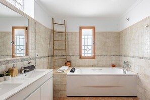 A modern bathroom with a large bathtub, a wooden ladder, and two windows with decorative frames. - Live the Ibiza Experience (Sant Josep de sa Talaia)