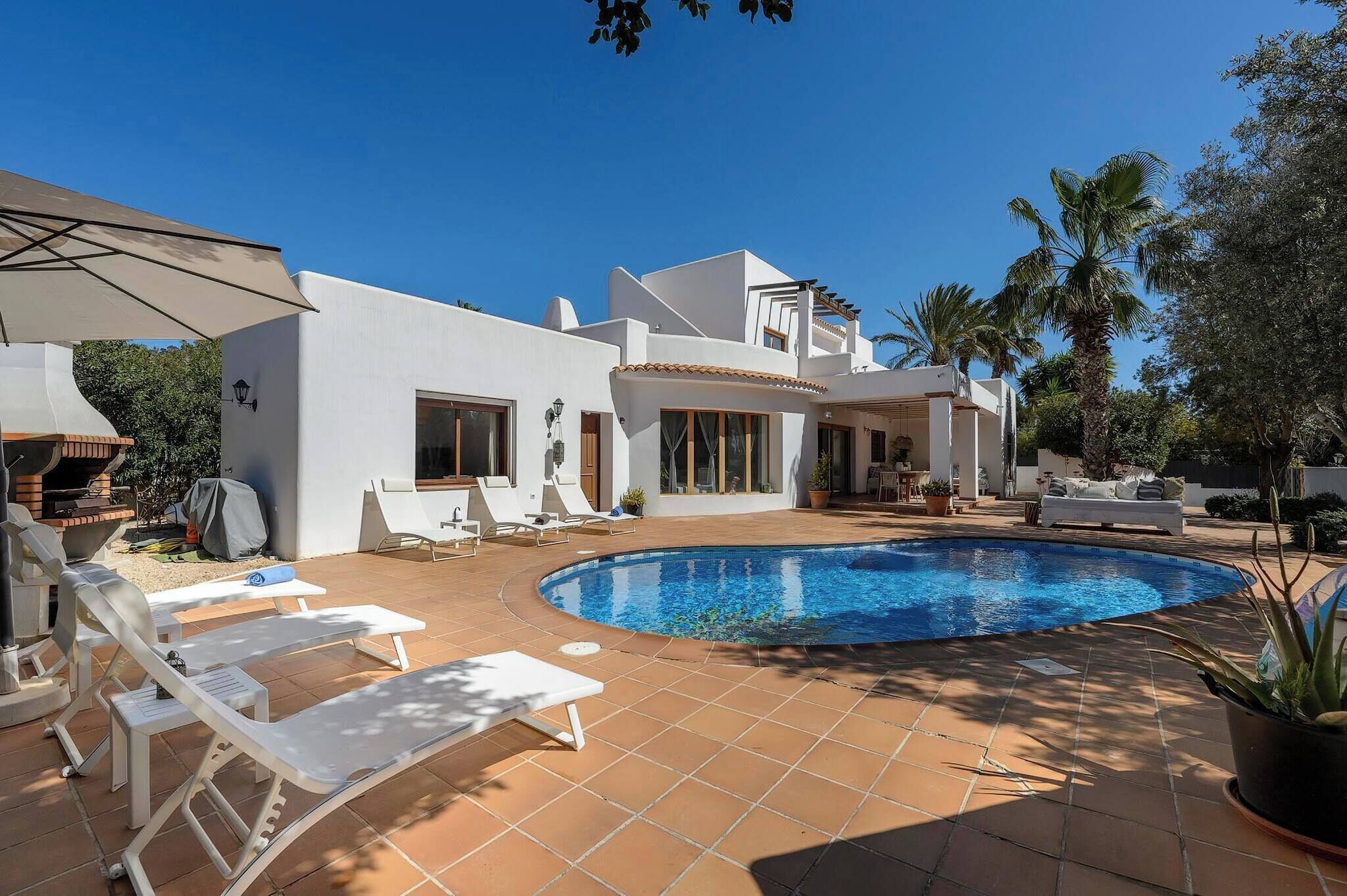Una casa moderna con piscina, zona de estar exterior y barbacoa.