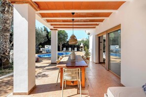 A covered outdoor dining area with a pool in the background. - Live the Ibiza Experience (Sant Josep de sa Talaia)