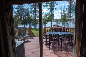 A deck with outdoor furniture, a view of a lake, and surrounding trees.