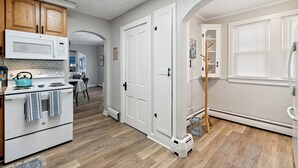 Eine Küche mit weißen Geräten, Holzschränken und Holzboden.