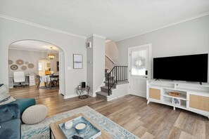 Un salón amplio con televisor grande, una escalera y un comedor.