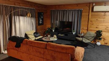 Un salon confortable avec un canapé, des fauteuils, une table basse et un téléviseur à écran plat.