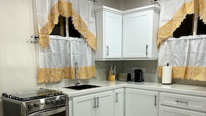 A kitchen with white cabinets, a stainless steel stove, and a sink. - Cozy 1-bedroom apartment in lovely Castries with AC (Castries)