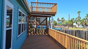 Eine Holzterrasse mit Blick auf eine Palme und einen strahlend blauen Himmel.