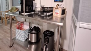 Eine Küchenzeile mit Kaffeemaschine, Wasserkocher, Toaster und einem über der Arbeitsplatte angebrachten Fernseher.