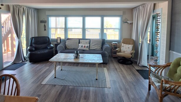 Ein geräumiges Wohnzimmer mit einer Couch, Sesseln, einem Couchtisch und einem Deckenventilator.