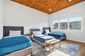 A modern bedroom with two beds, a wooden ceiling, and large windows. - Sleeps 10 • New Modern Home by Swamp Rabbit Trail (Greenville)