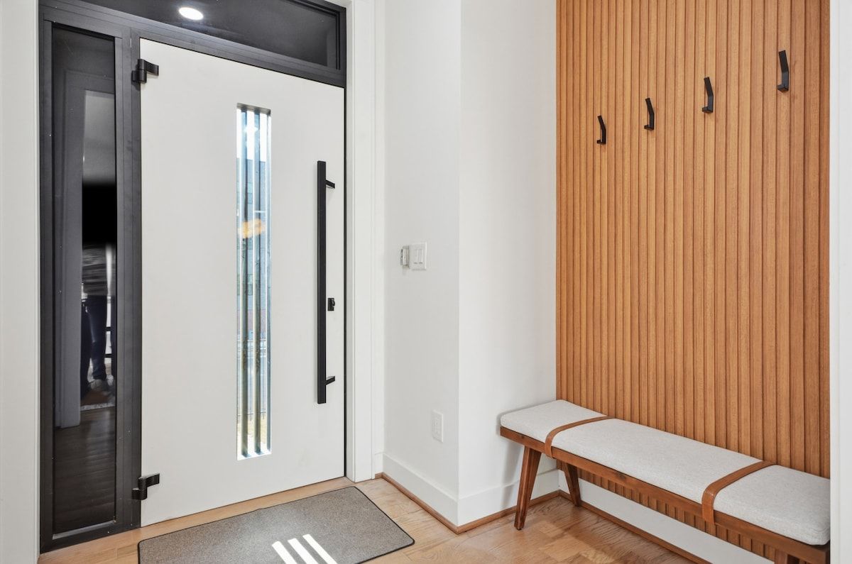 A room with a bench, a door with a vertical handle, and a wooden panel wall.