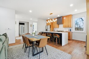 A modern kitchen with wooden cabinets, a central island, and pendant lighting. - Sleeps 10 • New Modern Home by Swamp Rabbit Trail (Greenville)