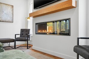 A modern living room with a fireplace, a mounted TV, and a comfortable seating area. - Sleeps 10 • New Modern Home by Swamp Rabbit Trail (Greenville)