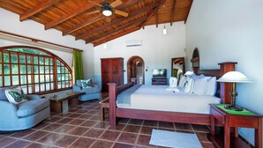 Une pièce spacieuse avec un grand lit, un canapé, un plafond en bois et un téléviseur.