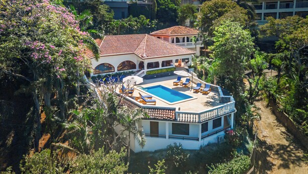Un bâtiment à deux étages doté d’une piscine, de chaises longues et d’un patio couvert.