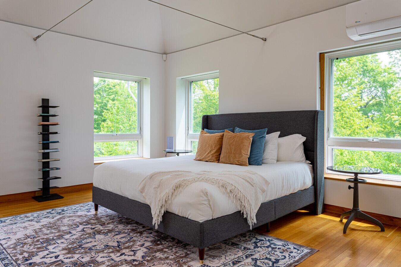 Un dormitorio moderno con una cama grande, una estantería y una mesita junto a la ventana.