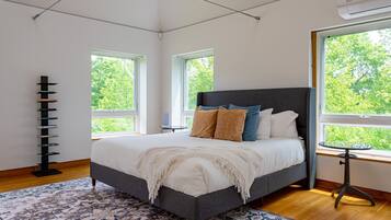 Un dormitorio moderno con una cama grande, una estantería y una mesita junto a la ventana.