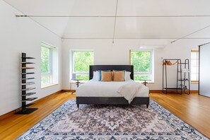 Un dormitorio moderno con una cama grande, una alfombra estampada y una estantería empotrada.
