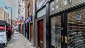 Een smalle straat met gesloten winkels en een zwarte deur met een raam.