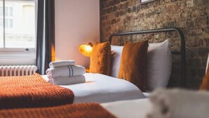 Een hotelkamer met een bakstenen muur, een bed met wit beddengoed en een radiator.
