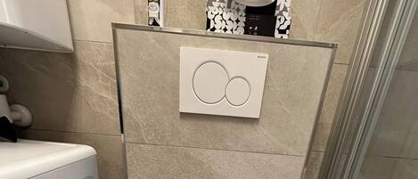 Ein modernes Badezimmer mit Toilette, Waschmaschine und Duschbereich.