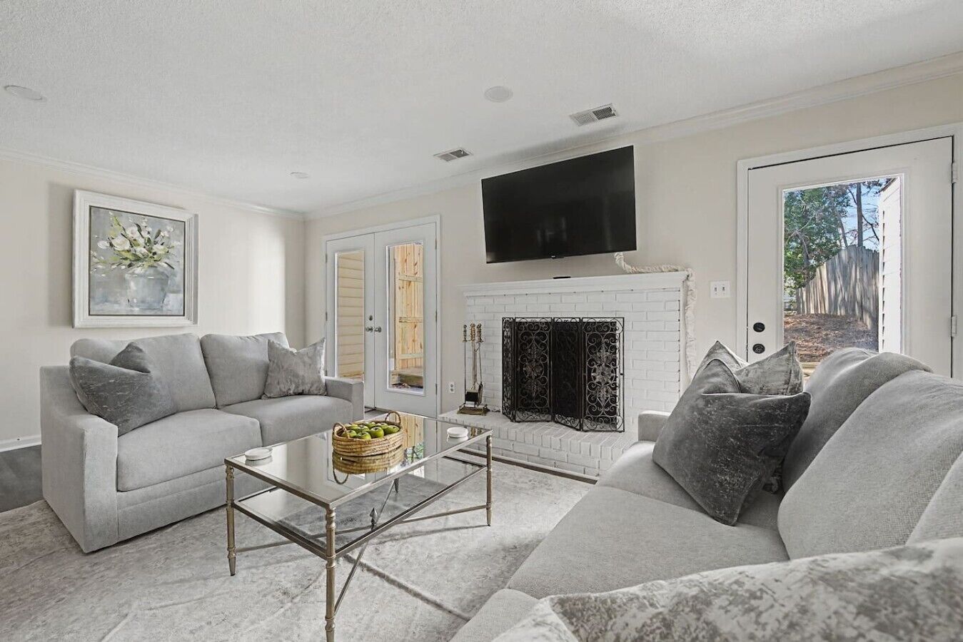 A living room with a fireplace, a sofa, a coffee table, and a television mounted above the fireplace.