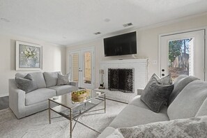 A living room with a fireplace, a sofa, a coffee table, and a television mounted above the fireplace. - Beautiful Home off Acton Road, 5 Minutes to Summit & 280 (Birmingham)