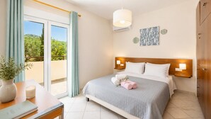 Ein Hotelzimmer mit Bett, Nachttischlampen, Blick ins Grüne und einer Topfpflanze.