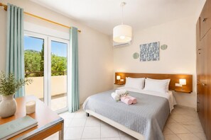 A hotel room with a bed, bedside lamps, a view of greenery, and a potted plant. - Villa Korini - Four Bedroom Villa, Sleeps 8 (Achlades)