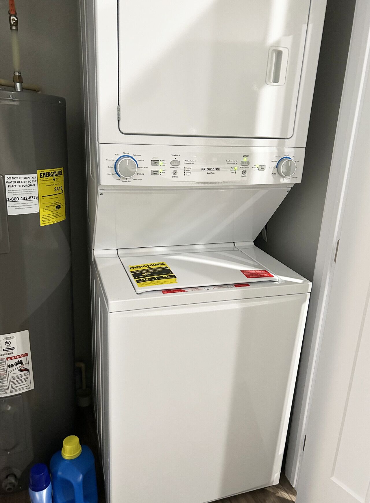A compact washer and dryer unit with a control panel, a water heater, and a caution label.